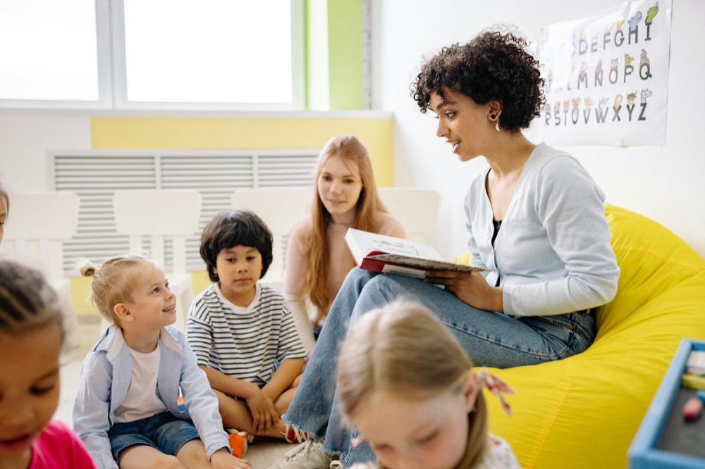 A teacher reads a picture book to a group of young children in a Head Start classroom
